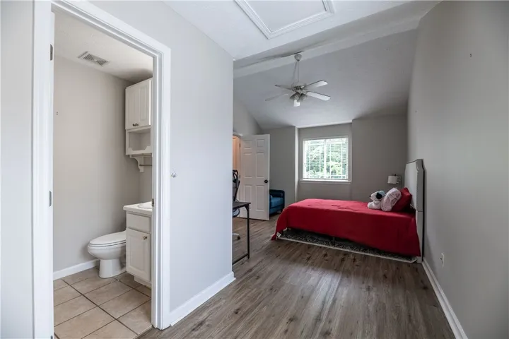 The private bedroom offers an ensuite bathroom, wood floors, and a vaulted ceiling with a ceiling fan.