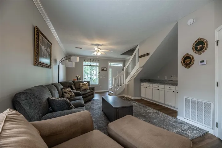 A welcoming living area with rich hardwood flooring and a stylish staircase.