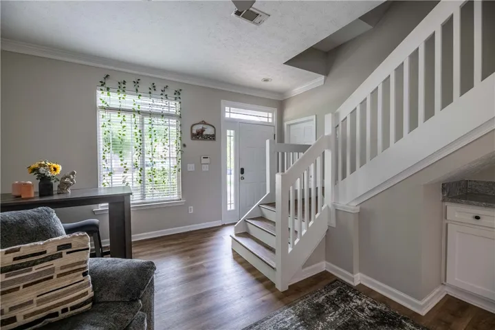 Natural light floods this inviting entryway, showcasing pristine wood flooring and a classic staircase.