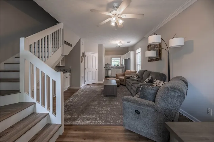 An open concept living area boasts elegant hardwood flooring, flowing into a well-appointed kitchen.