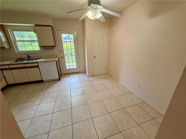 This bright kitchen features durable tile flooring, a window above the sink, and direct outdoor access.