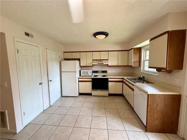 This spacious kitchen offers a practical layout with ample cabinetry and essential appliances.