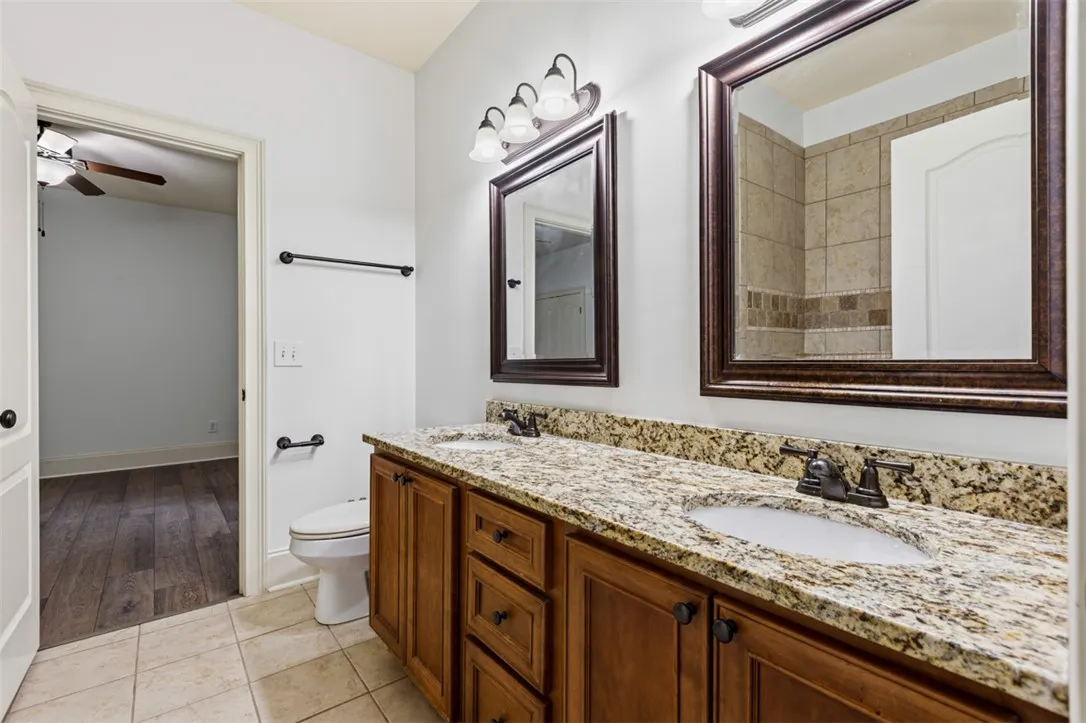 This bathroom features a double vanity with granite counters and rich wood cabinetry.
