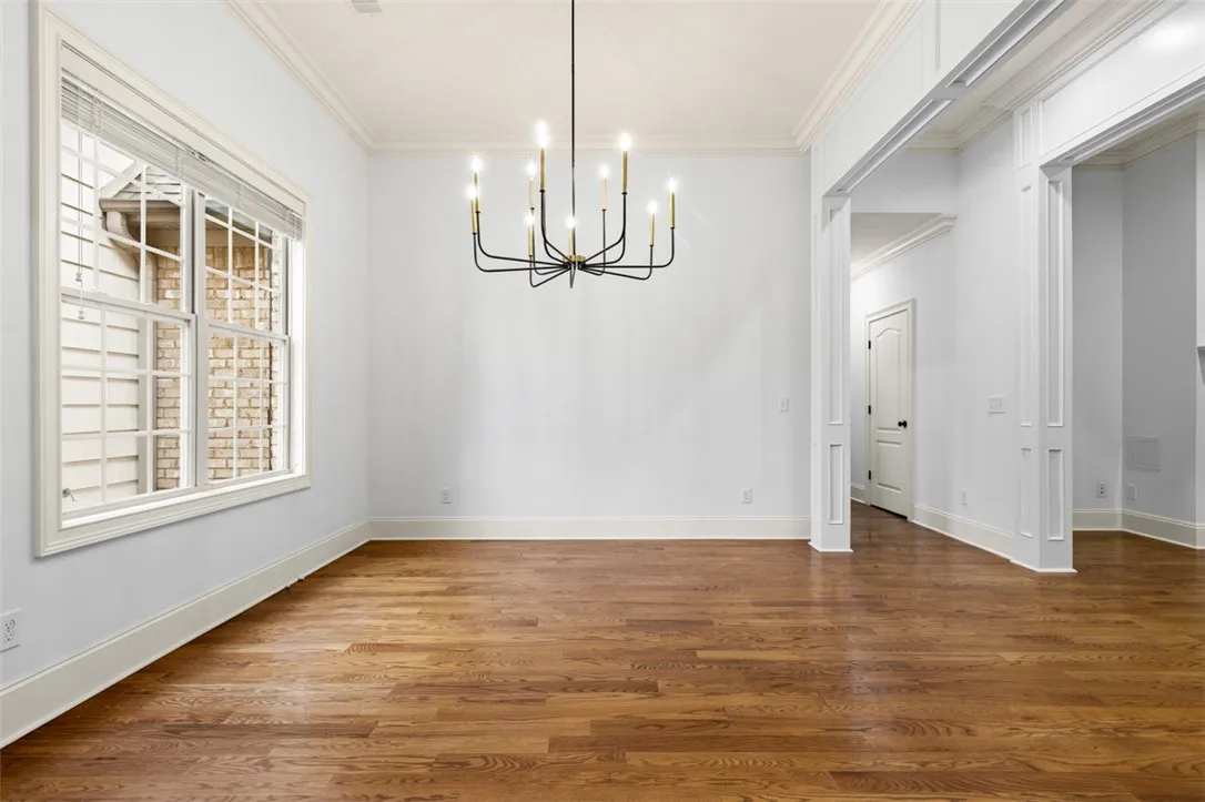 This bright space features rich wood flooring, crown molding, and a classic chandelier.