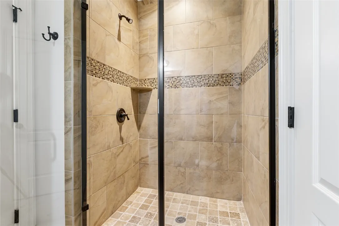 This spacious shower features elegant tile work and practical built-in shelving.