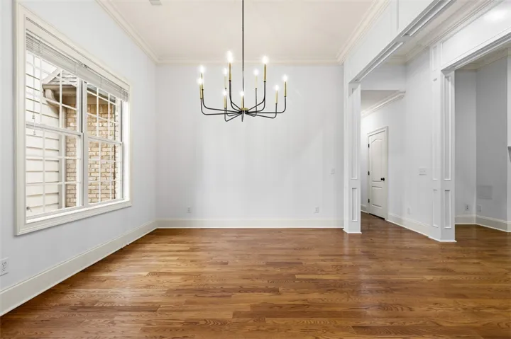 This bright space features rich wood flooring, crown molding, and a classic chandelier.