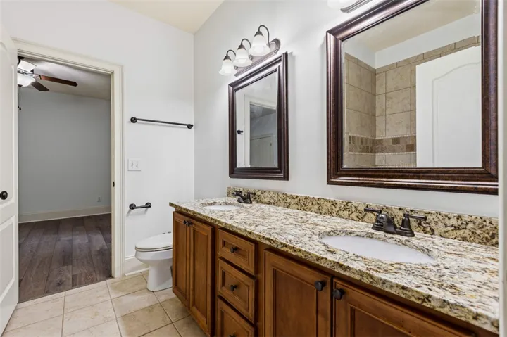 This bathroom features a double vanity with granite counters and rich wood cabinetry.