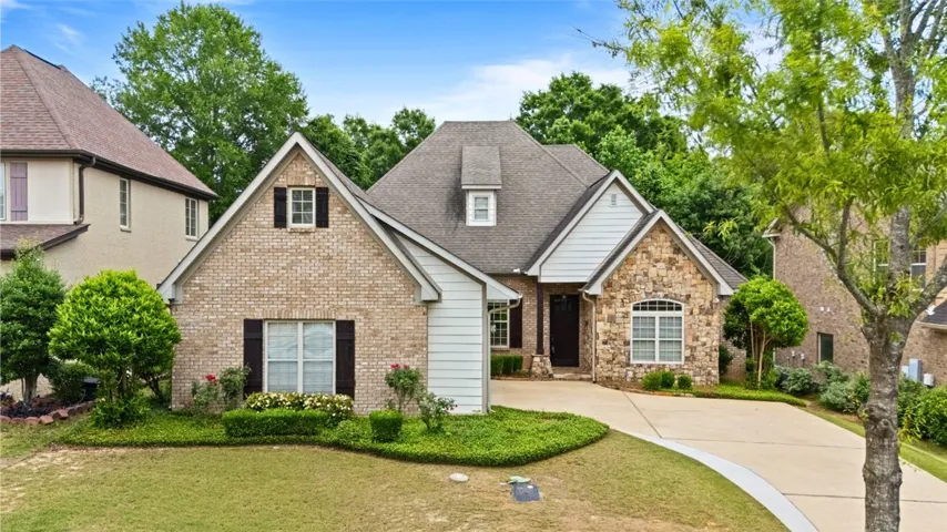 This charming home features a mix of brick and stone, a classic roof, and a welcoming driveway.