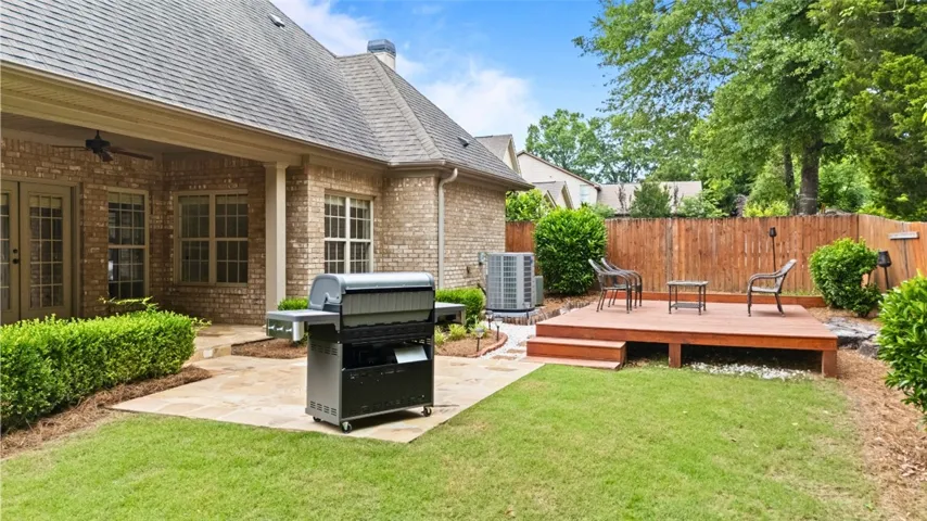 This spacious yard features a wooden deck and a charming patio, perfect for outdoor living.