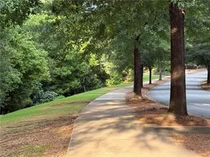 Walk along the inviting pathway bordered by lush greenery and mature trees.