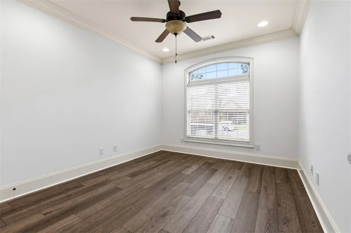 This bright space features rich flooring, an arched window, and overhead lighting.