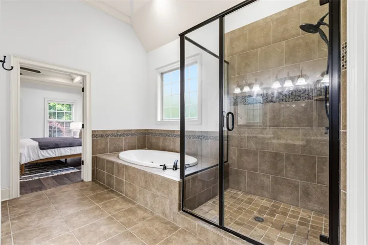 This primary bathroom offers a spacious layout, with a soaking tub and a separate glass-enclosed shower.