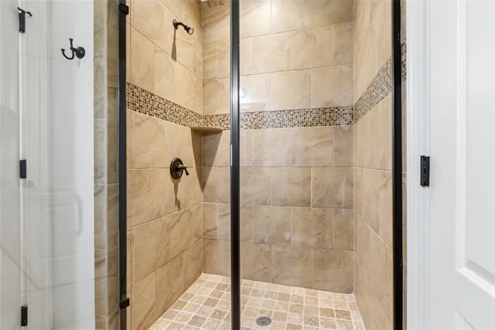 This spacious shower features elegant tile work and practical built-in shelving.