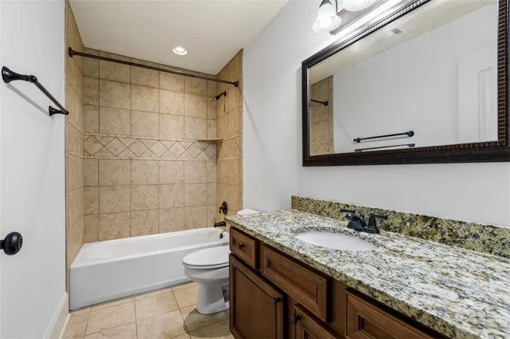 This bathroom features elegant granite counters and ceramic tile flooring, creating a polished and inviting space.