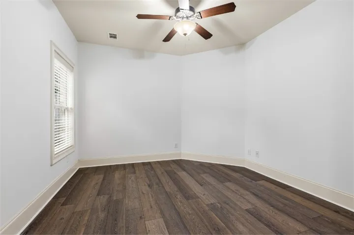 This spacious room features rich hardwood flooring, a ceiling fan, and ample natural light.