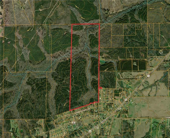 This aerial view showcases a diverse landscape with natural contours and adjacent community.