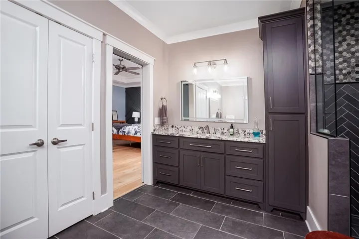 Refined bathroom with a dual vanities, sleek dark cabinetry, and sophisticated tile work in the shower.