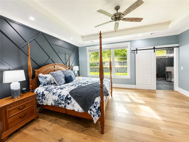 Hardwood floors and generous natural light create an inviting sanctuary in this spacious primary bedroom.