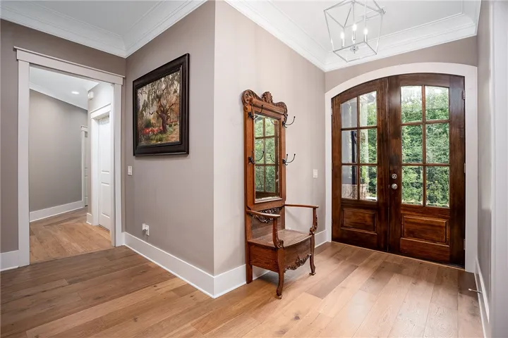 Rich hardwood floors welcome guests into an inviting entry featuring a striking arched door.