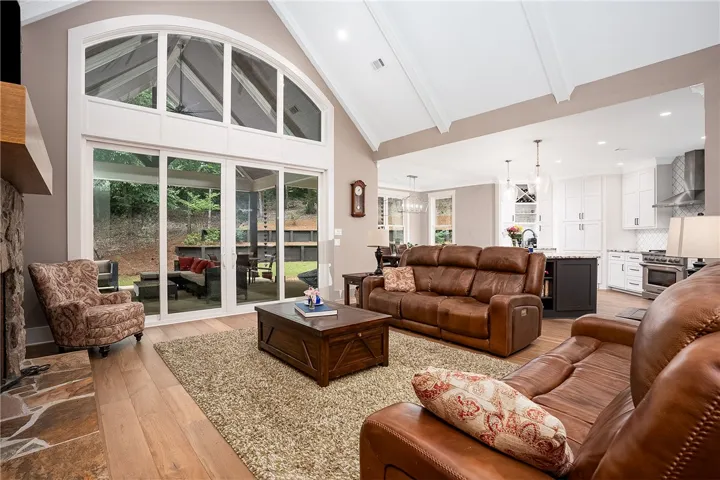 An open floorplan seamlessly connects the living area to a chef's kitchen, all bathed in light from the vaulted ceiling and wall of windows.
