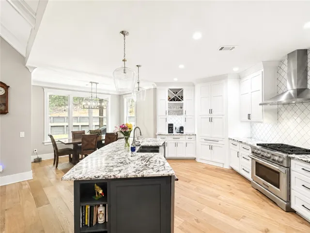 A well-appointed kitchen showcasing a spacious island with granite counters and rich hardwood flooring.