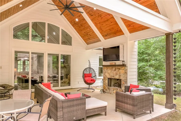 An inviting outdoor living space features a stone, wood burning fireplace and vaulted wood-beamed ceilings.