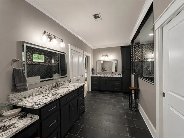 Dual vanities with granite counters provide ample space in this well-appointed primary bathroom.