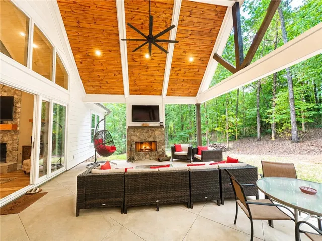 An inviting covered patio featuring a stone fireplace and rich wood ceiling, perfect for tranquil outdoor living.
