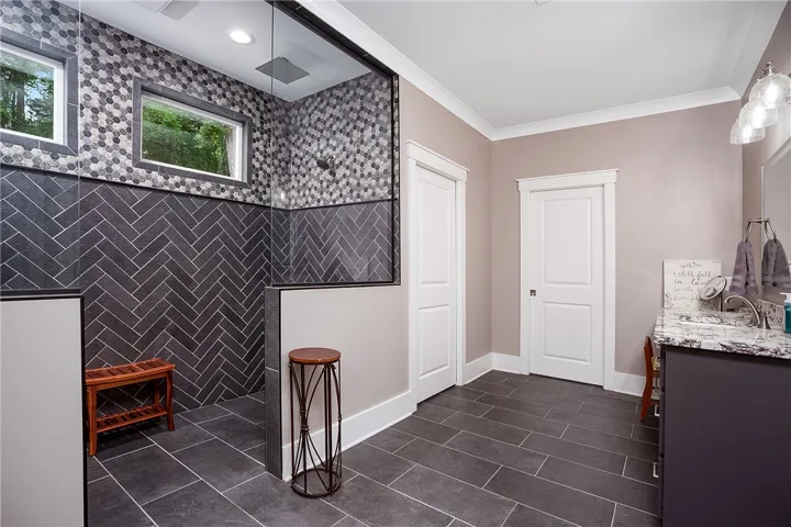 A contemporary bathroom with a spacious zero entry shower featuring elegant herringbone and mosaic tile work.