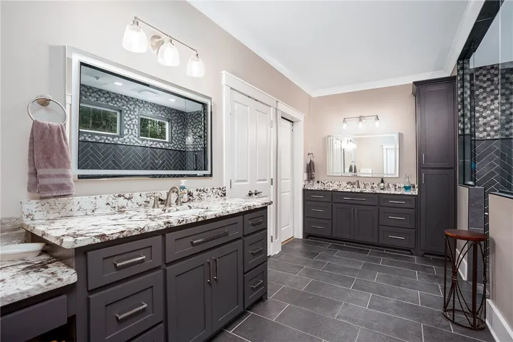 Granite counters and spacious dark cabinetry enhance this modern bathroom's design.