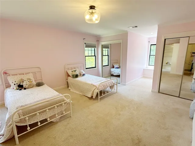 This spacious bedroom offers ample natural light and a comfortable, inviting atmosphere.