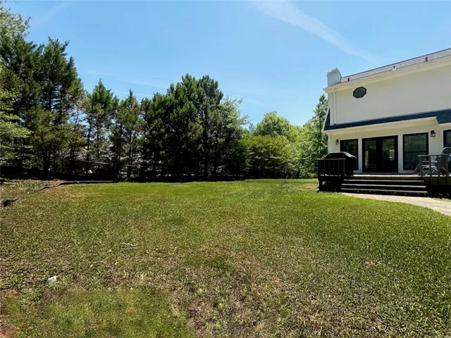 A spacious yard extends from a lovely home, offering abundant outdoor possibilities and mature trees.