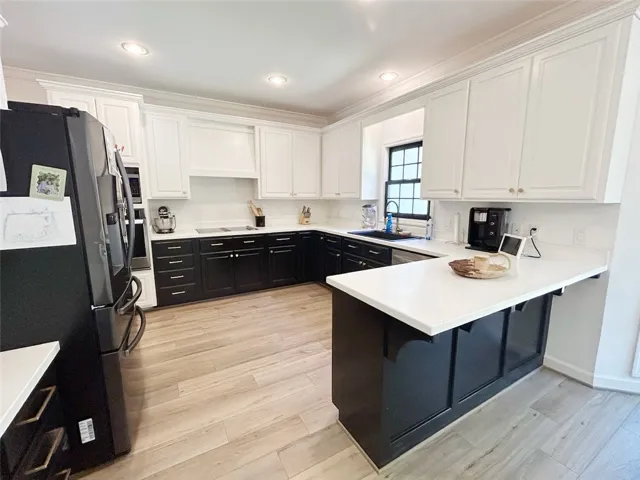 This modern kitchen features a spacious layout with white countertops and light-colored flooring.