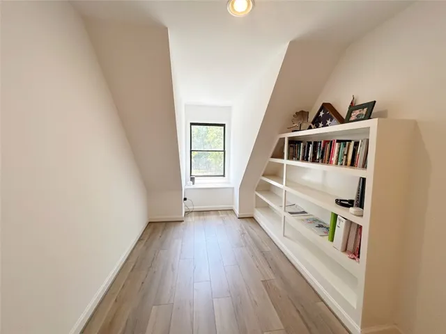 This versatile attic space features built-in shelving, a large window, and durable flooring.