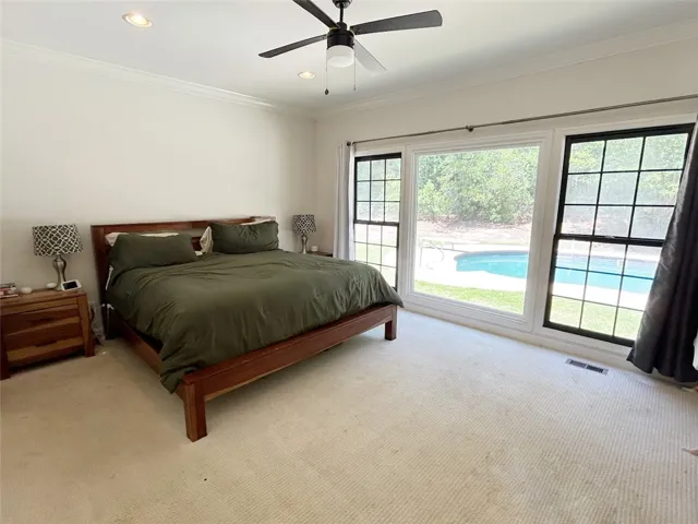 This spacious bedroom offers serene views of the outdoor pool and lush greenery.