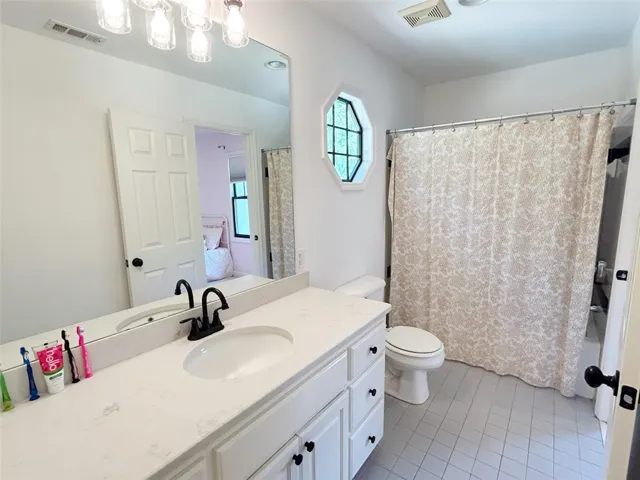 This bright bathroom features a vanity with ample counter space and a classic shower.