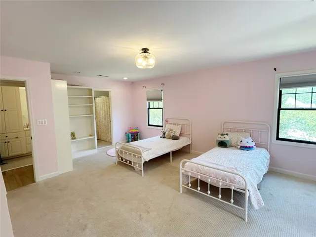 This spacious bedroom offers ample natural light and a comfortable setting.