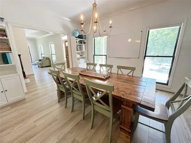 This bright dining area features an open floorplan with light wood flooring and built-in shelving.