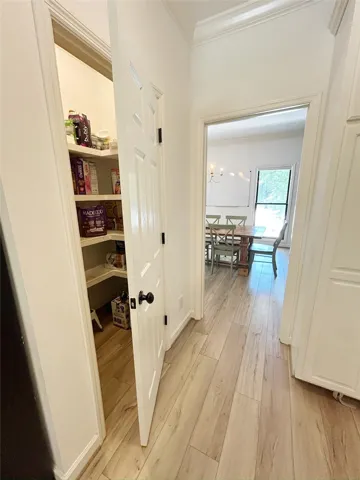 This spacious pantry provides convenient storage, complemented by elegant wood flooring throughout the area.