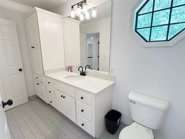 This bathroom features an elegant vanity with ample storage and a unique octagonal window.