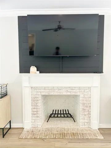 This living space features a cozy brick fireplace with a decorative mantle and elegant crown molding.