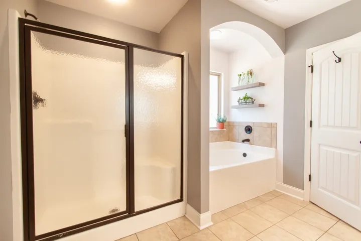 This bright bathroom features a spacious tub and a walk-in shower for ultimate comfort.