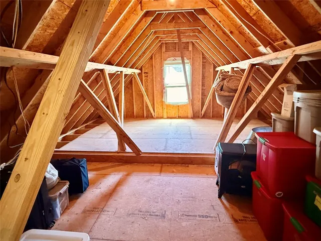 Attic with exposed wooden beams provides ample storage or potential for future expansion.