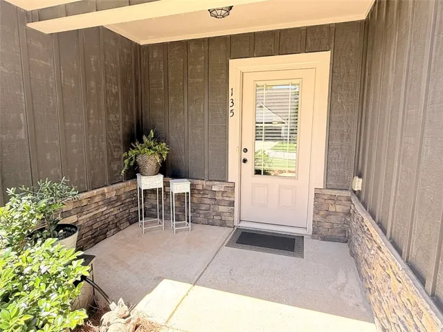 The welcoming entryway features durable siding and a charming stone accent, offering a warm approach.