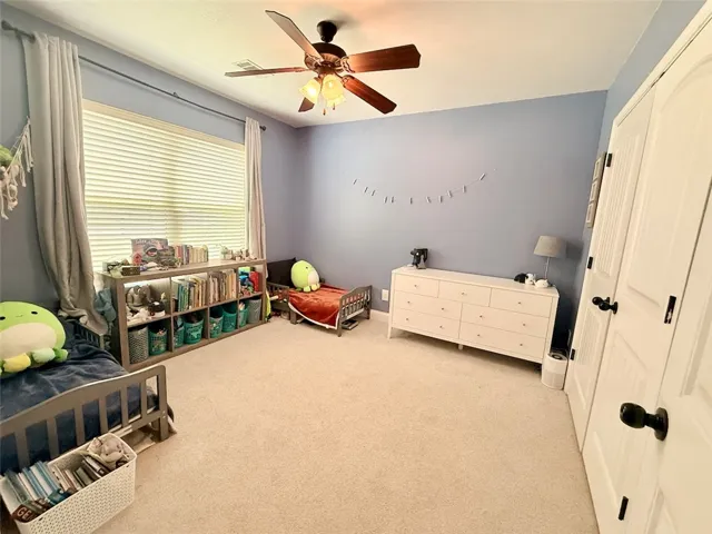 Bedroom 2 offers comfortable carpeting and a ceiling fan.