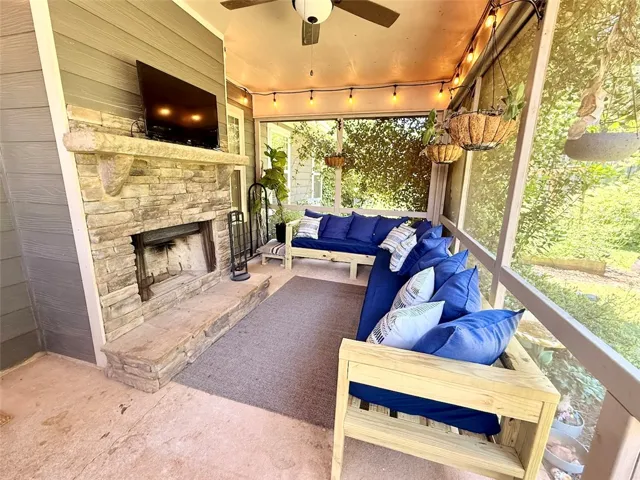 This inviting screened porch features a stone fireplace for cozy outdoor gatherings.