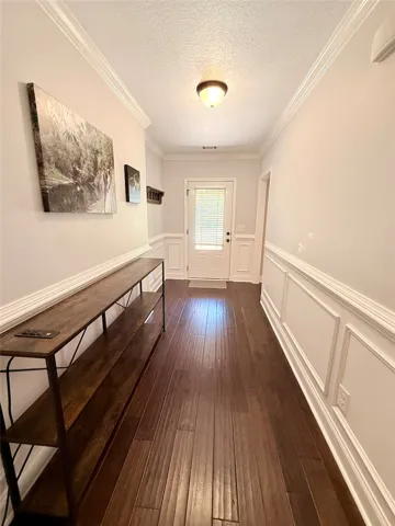 This inviting hallway features rich hardwood flooring and classic wainscoting.
