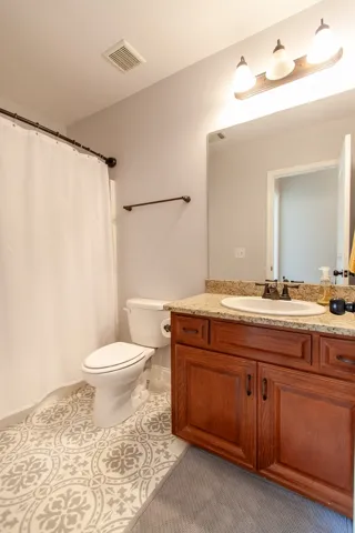 This clean bathroom features a spacious vanity with ample storage and a stylish patterned tile floor.