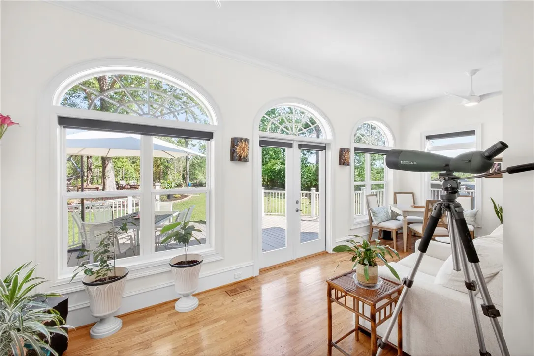 This bright living space features hardwood floors, tall arched windows, and a ceiling fan, creating an inviting atmosphere.