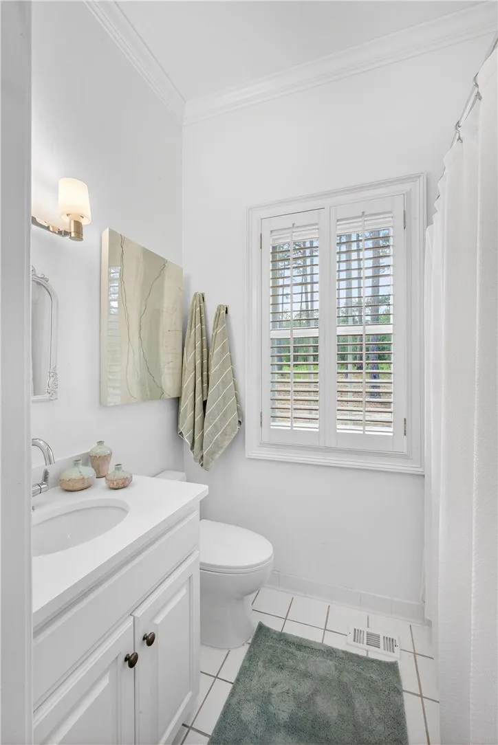 This bright bathroom features crown molding and a window offering natural light.
